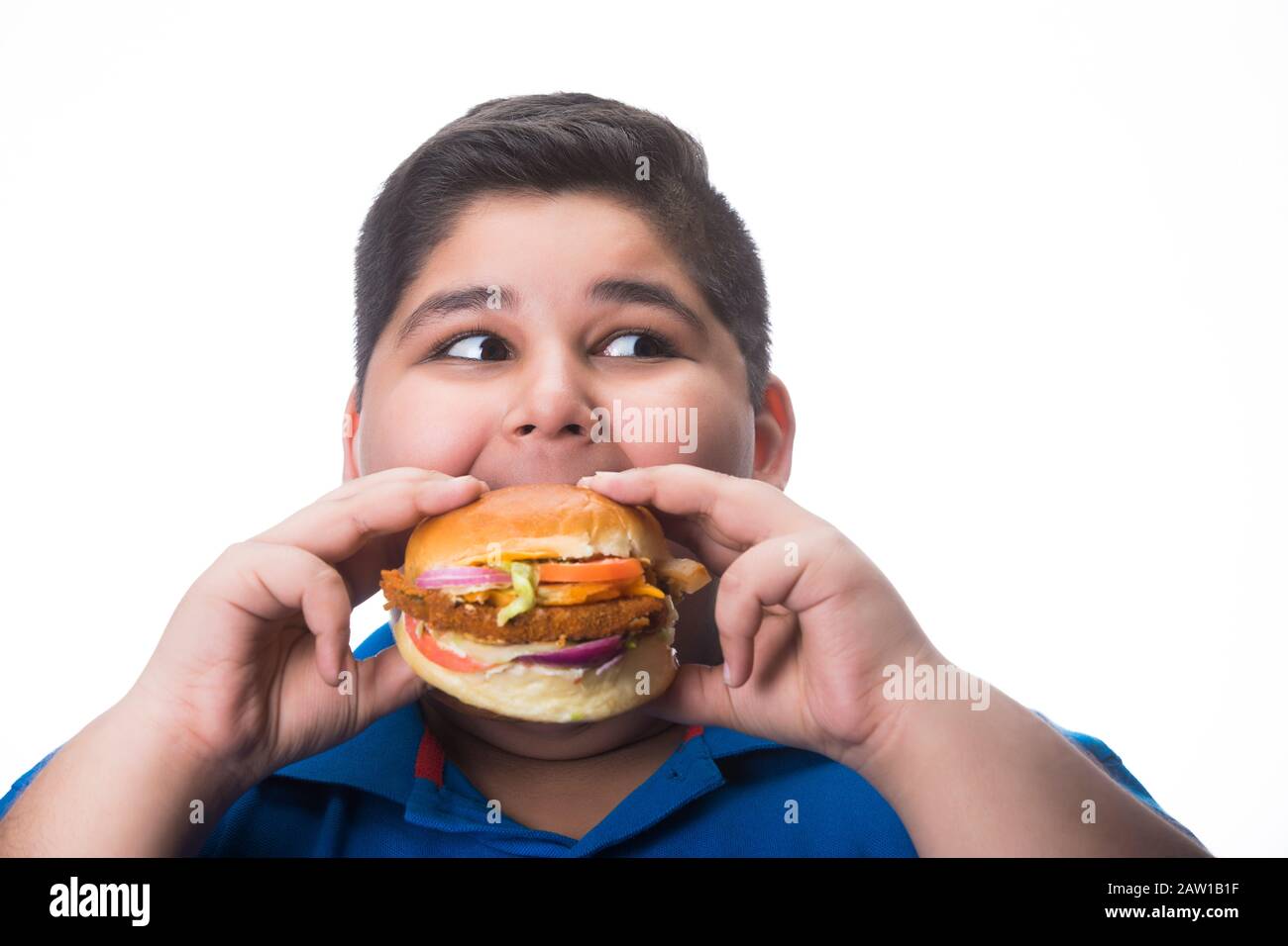 Young boy hungrily eating a burger in hand. (Obesity Stock Photo - Alamy