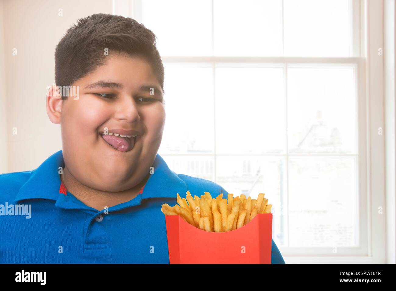 Young boy hungrily looking at fries. (Obesity Stock Photo - Alamy