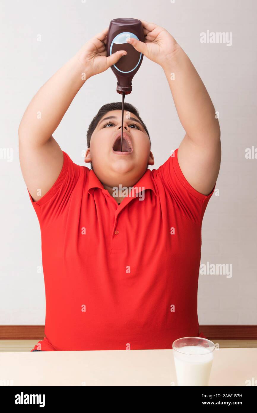 Young boy drinking chocolate syrup directly from the bottle. (Obesity) Stock Photo