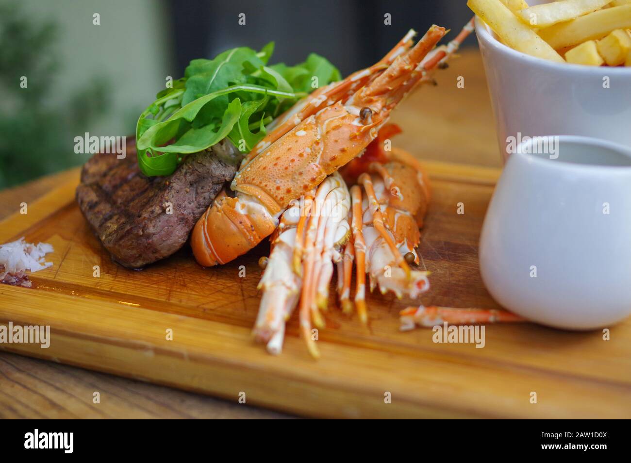 Surf and turf grilled lobster steak french fries on wood tray Stock