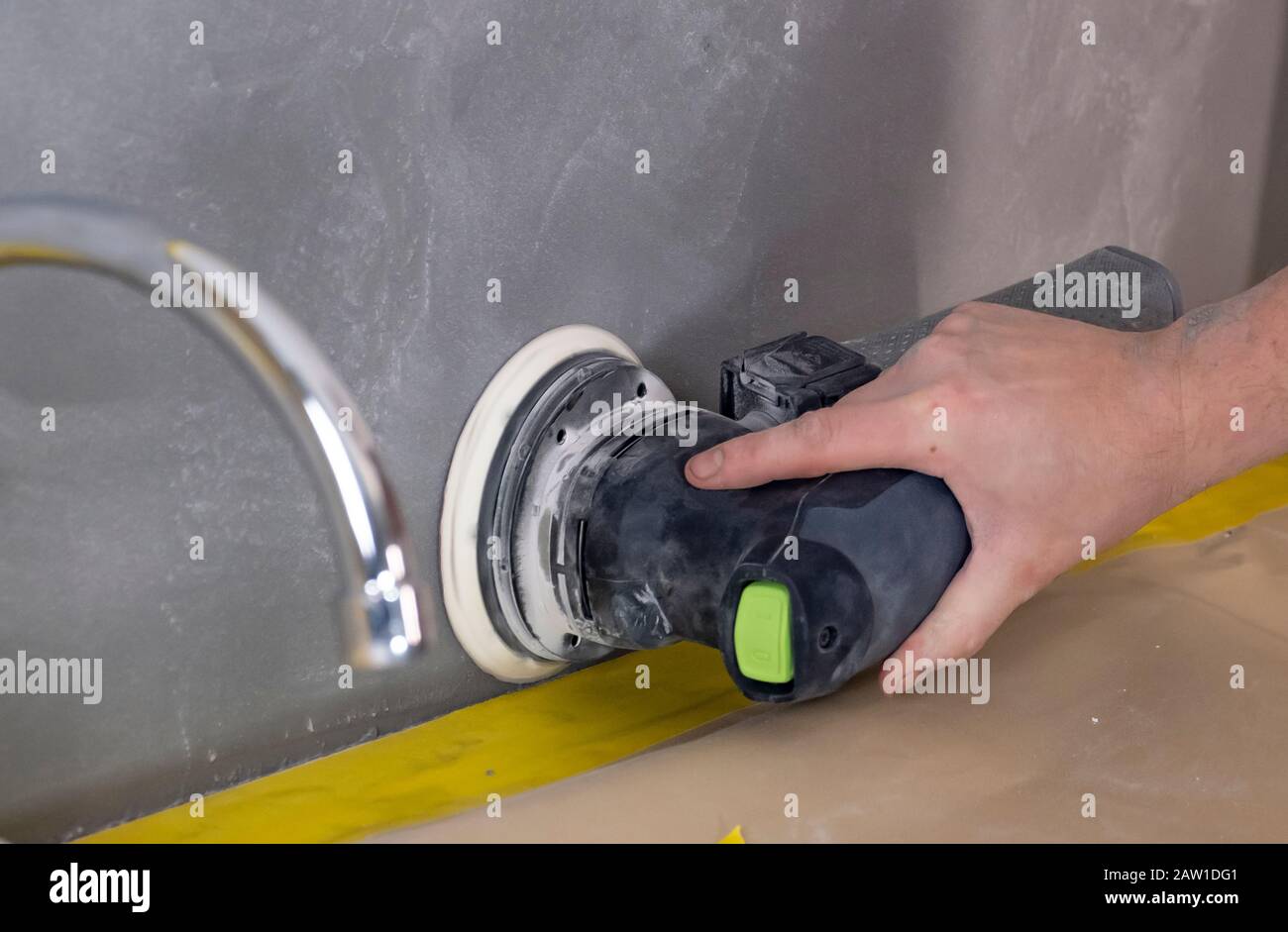 Randomorbit disc sander held in grip of man's hand, refinishing piece