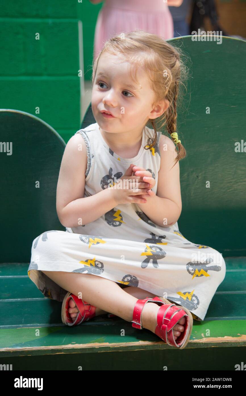 little girl sitting cross legged Stock Photo