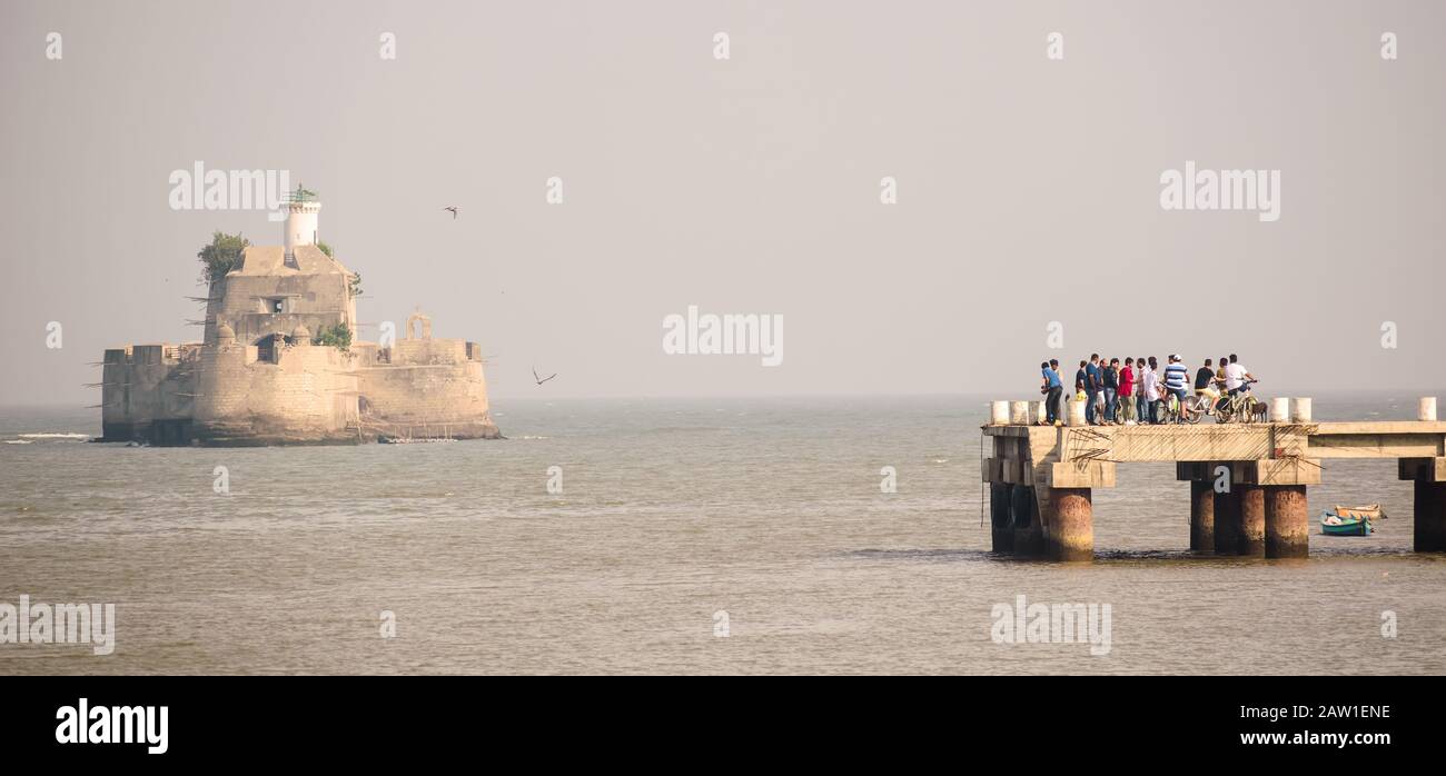 The Pani Kotha aka Fortim Do Mar, the ancient Portuguese island fortress in the middle of the sea. Tourists on bicycles enjoy the view from Diu jetty. Stock Photo
