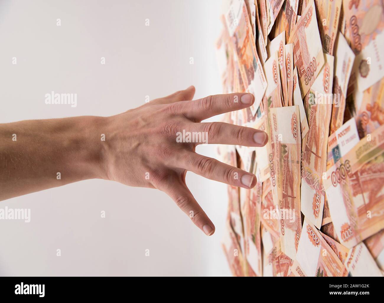 A man's hand reaches for a vertical cash flow of five thousand ruble bills. Stock Photo