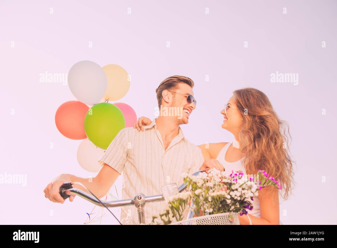 couple in love having fun on bikes with balloons and flowers Stock Photo