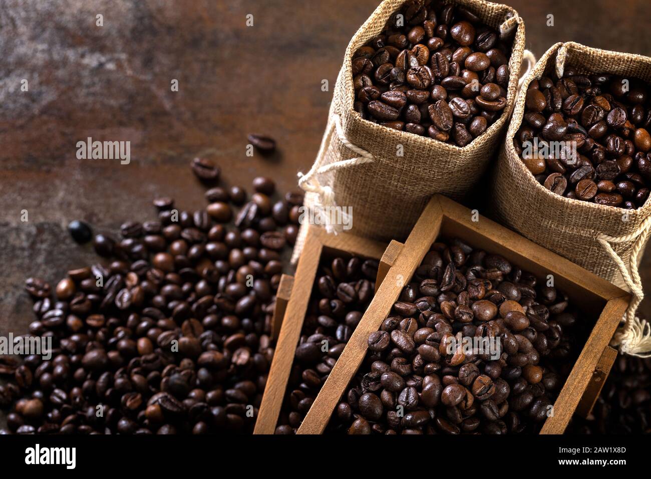 Jute bags and wooden containers filled with cofee beans on the rust ...