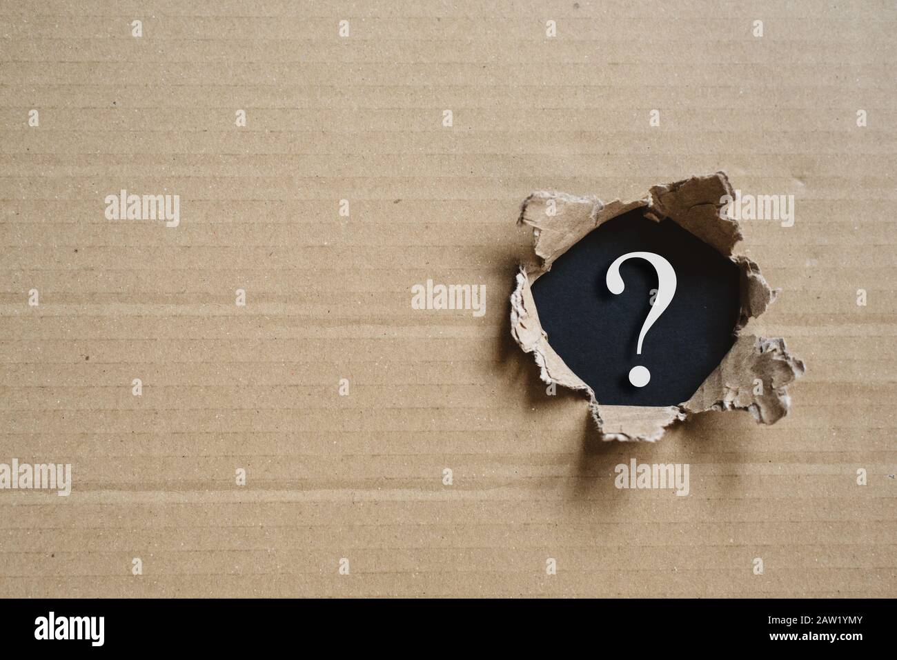 Torned corrugated box revealing question mark. Concept of mystery and uncertainty Stock Photo
