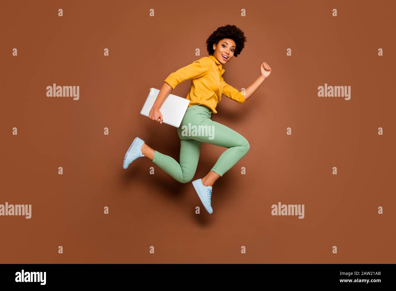 Full length photo of funky dark skin lady jump high hold notebook hurry classes lessons schoolgirl wear yellow shirt green pants footwear isolated Stock Photo