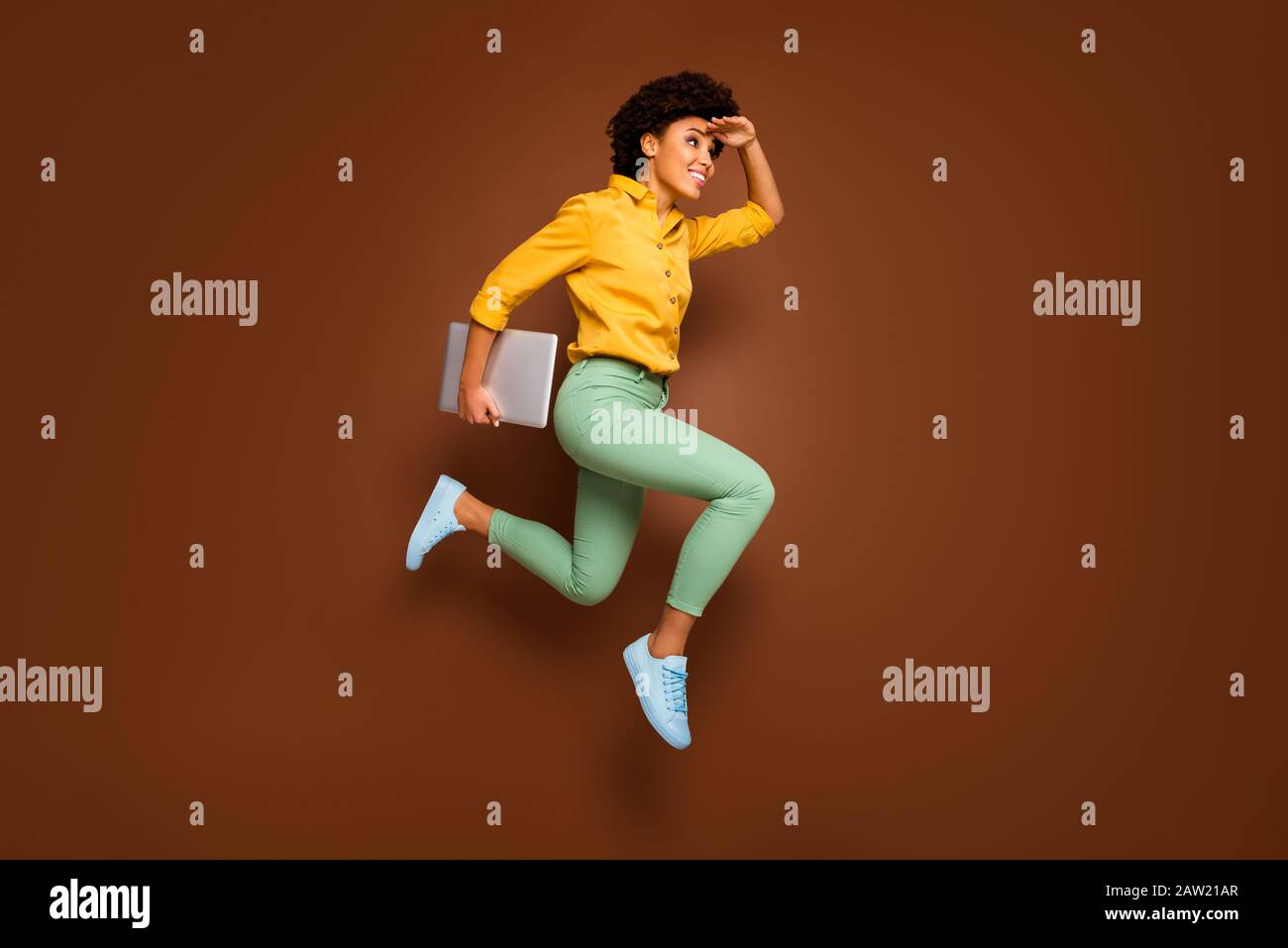 Full body photo of funky dark skin lady jump high hold notebook hurry lessons school see building close wear yellow shirt green pants footwear Stock Photo