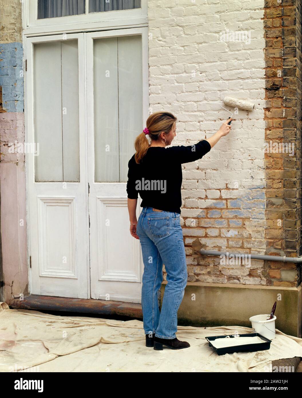 Woman painting a wall outside hi-res stock photography and images - Alamy