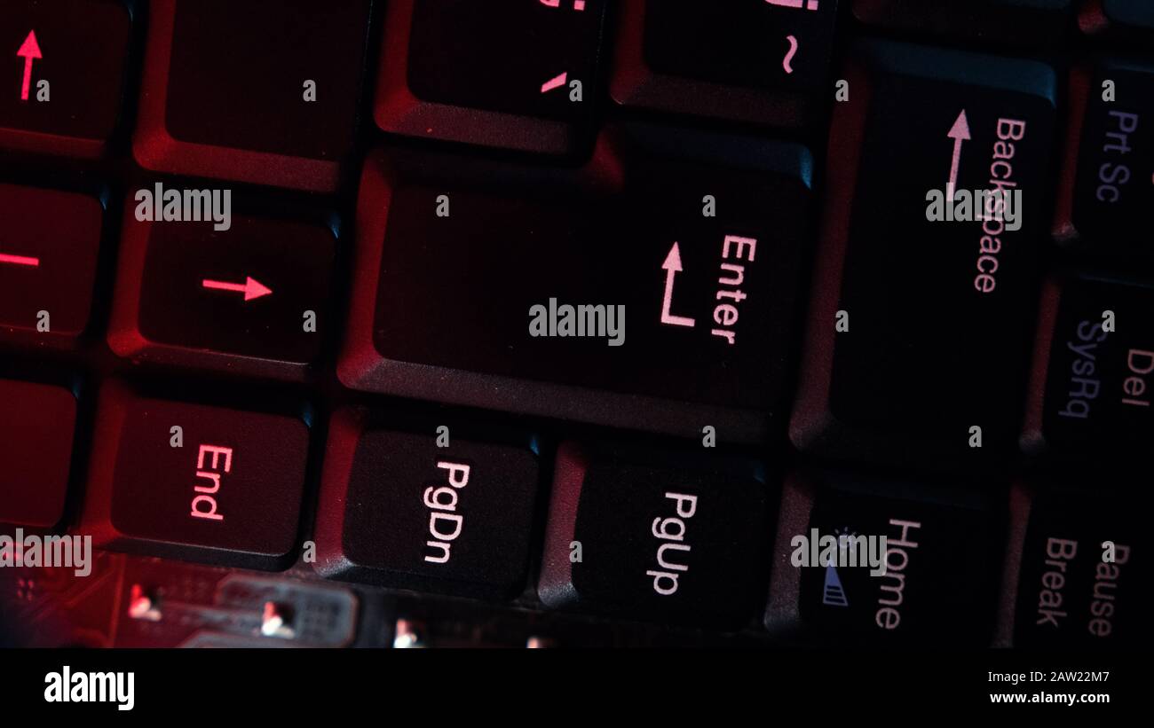 The computer keyboard, which is shot close to the abstract lights, is pressed at the enter. Hacking Concept. Stock Photo