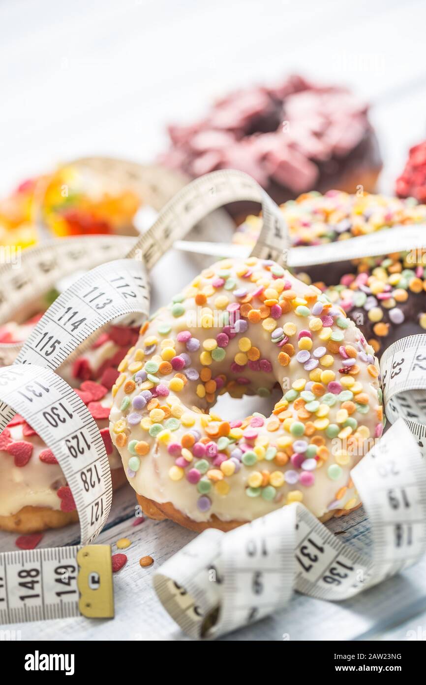 Sweet glazed donuts and measure tape on table. Stock Photo