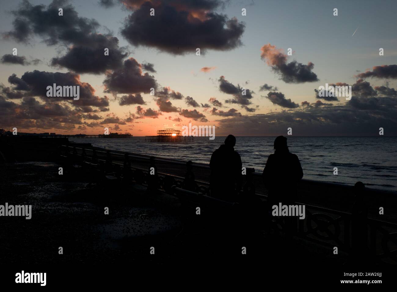 Couple watching sunrise over West Pier, Brighton Stock Photo