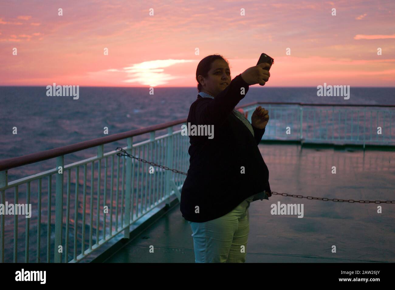 Woman taking selfie against sunset on a cross-channel ferry Stock Photo