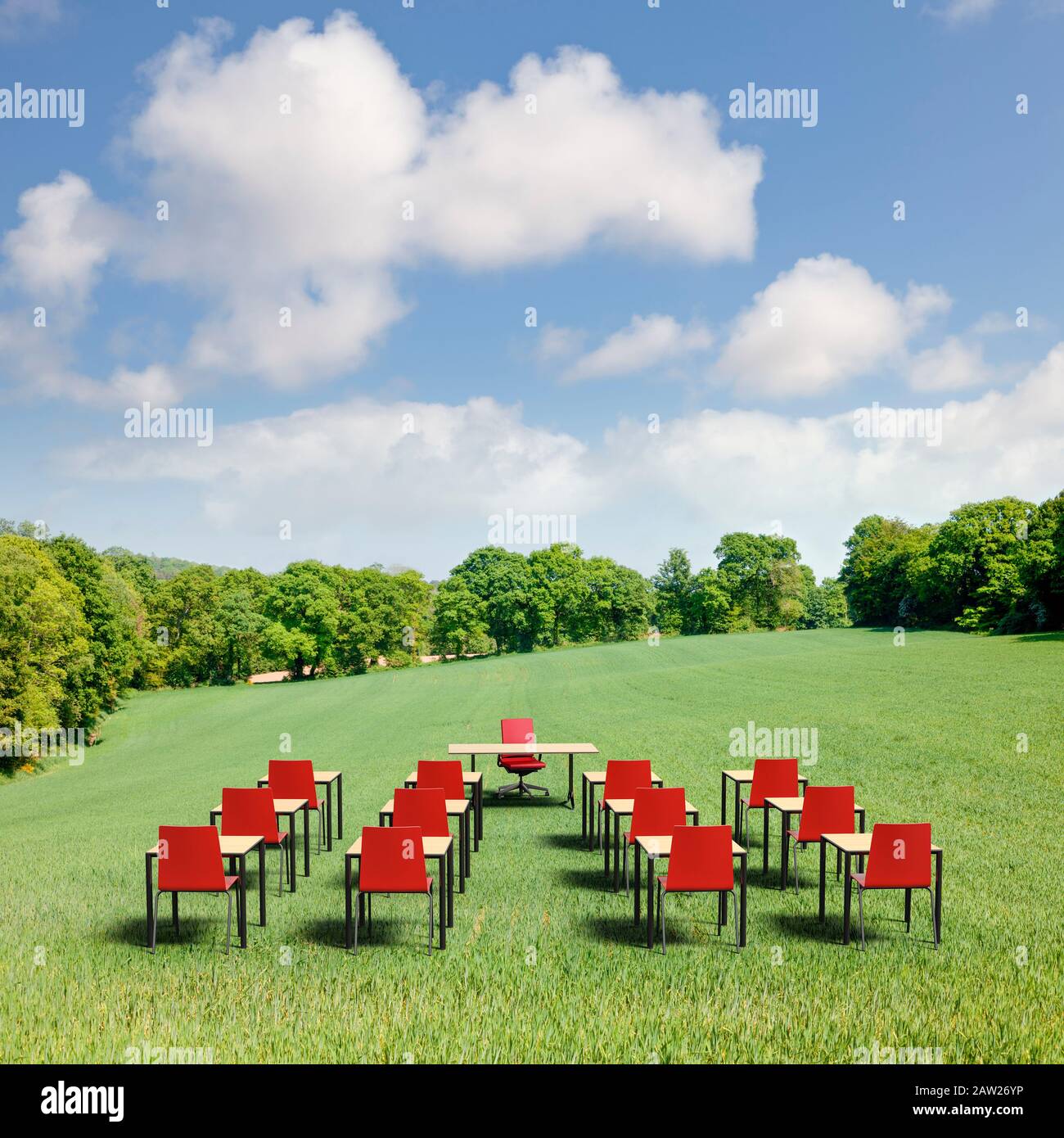 An outdoor school class in the open air with desks and chairs in a green field Stock Photo