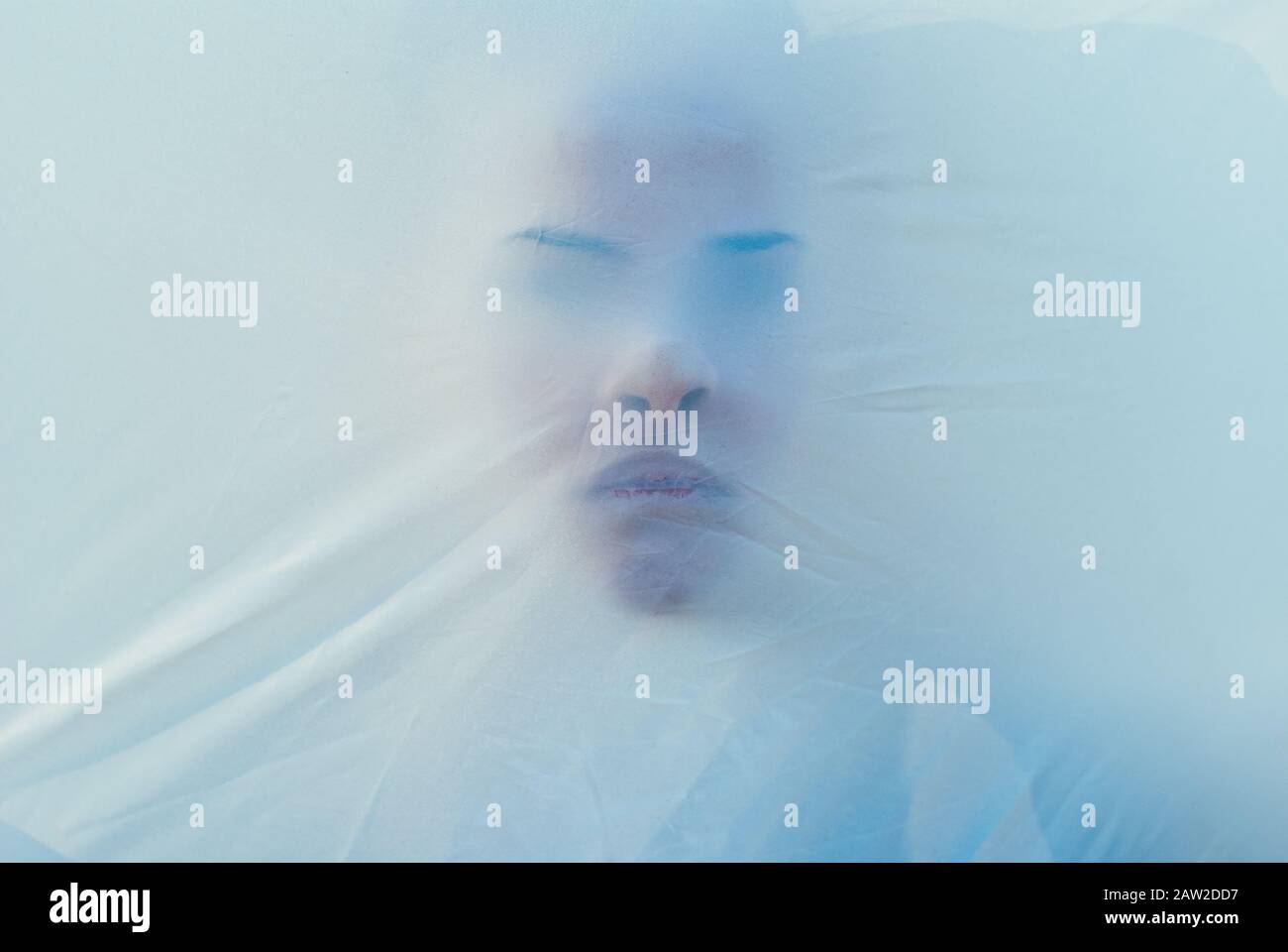 Beautiful female face through the fabric. Scary background Stock Photo