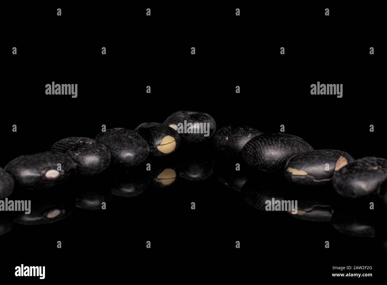 Group of ten whole black bean isolated on black glass Stock Photo