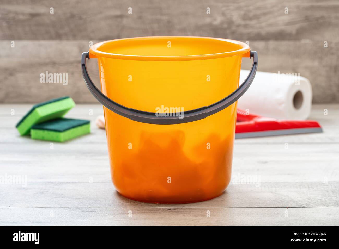 Cleaning bucket orange color on the floor, home interior wood floor background. Domestic household or business sanitary cleaning Stock Photo