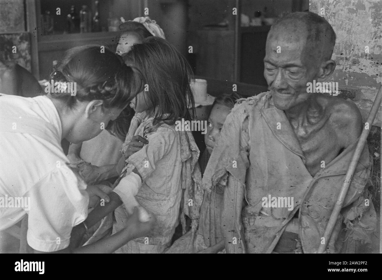 Photoreportage Palembang  Outpatient? Nurse commits little girl, right emaciated old man in rags Date: 1947 Location: Indonesia Dutch East Indies Stock Photo