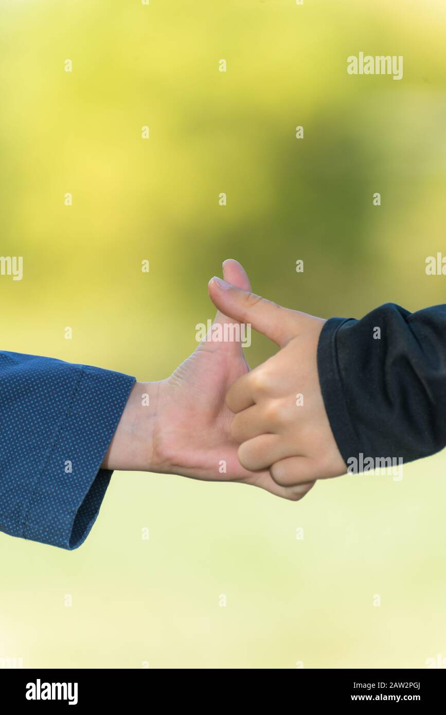 Two kids hands having a thumb war on a blurred background Stock Photo