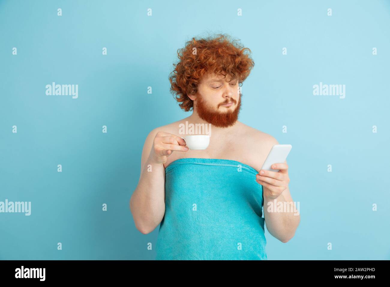 Portrait of young caucasian man in his beauty day and skin care routine. Male  model with natural red hair drinking coffee and watching social media. Body  and face care, natural, male beauty