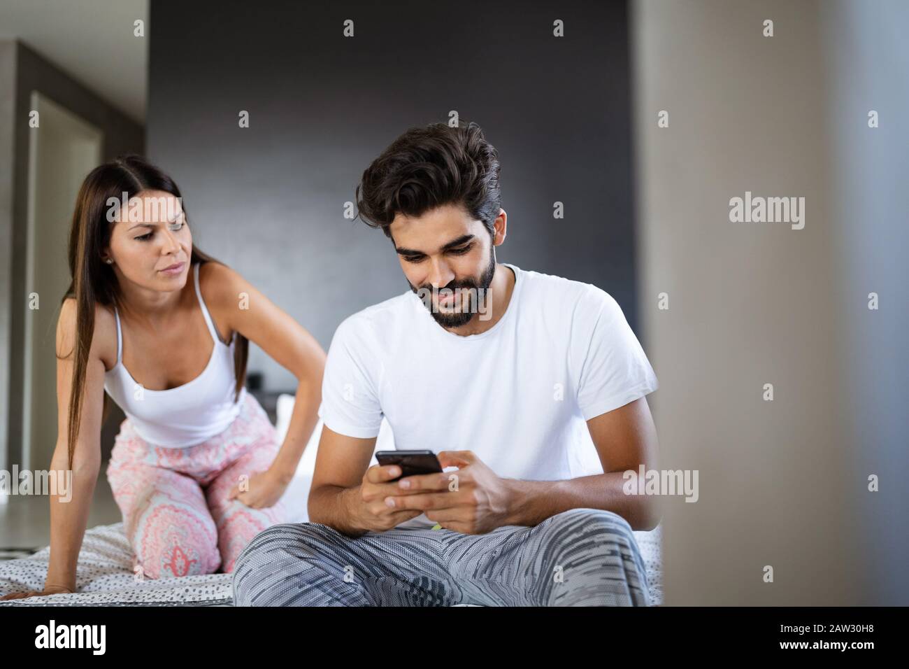 Young shocked wife caught husband on cheating snooping his messages with lover on smartphone Stock Photo