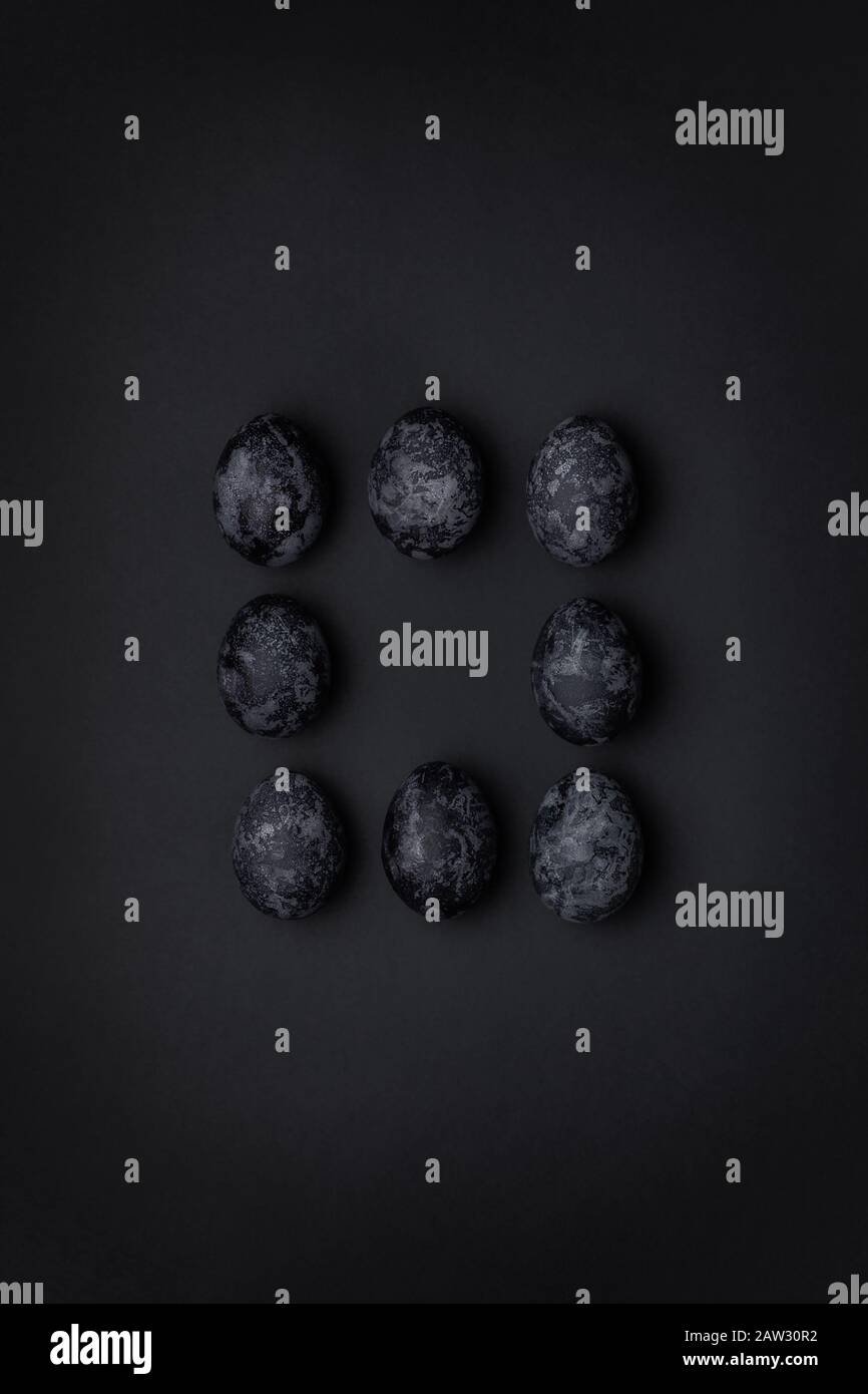 Handmade monochrome black textured painted eggs square pattern in the middle of composition on a black background. Happy Easter minimal concept Stock Photo