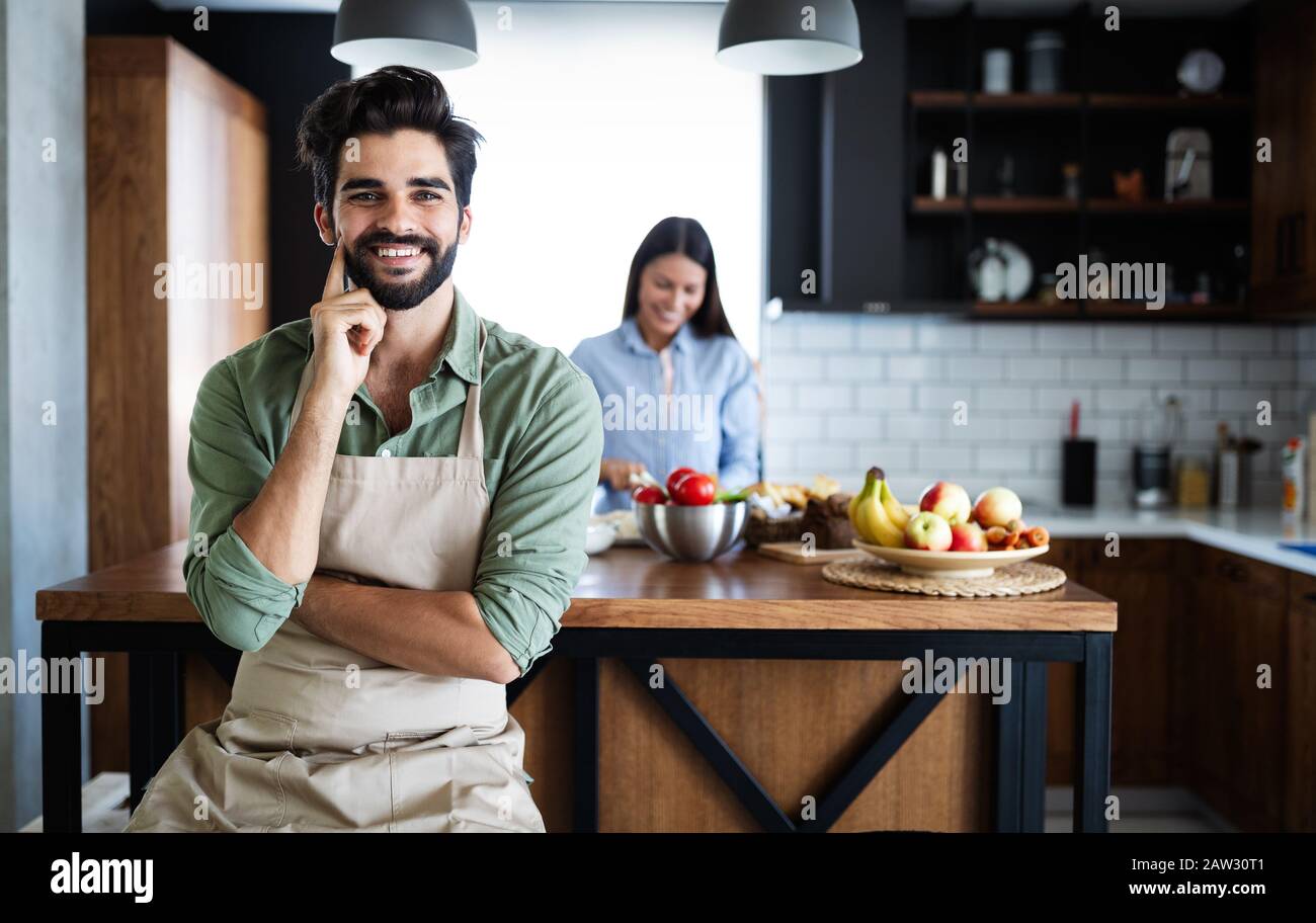Portrait of happy young couple cooking together in the kitchen at home. Stock Photo