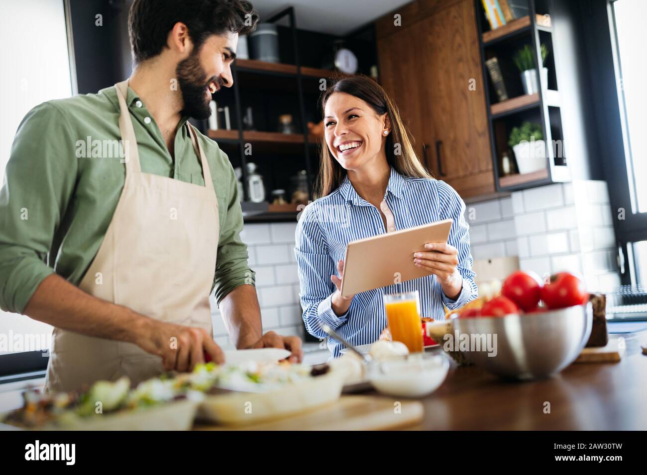 Happy couple cooking together in their kitchen Stock Photo