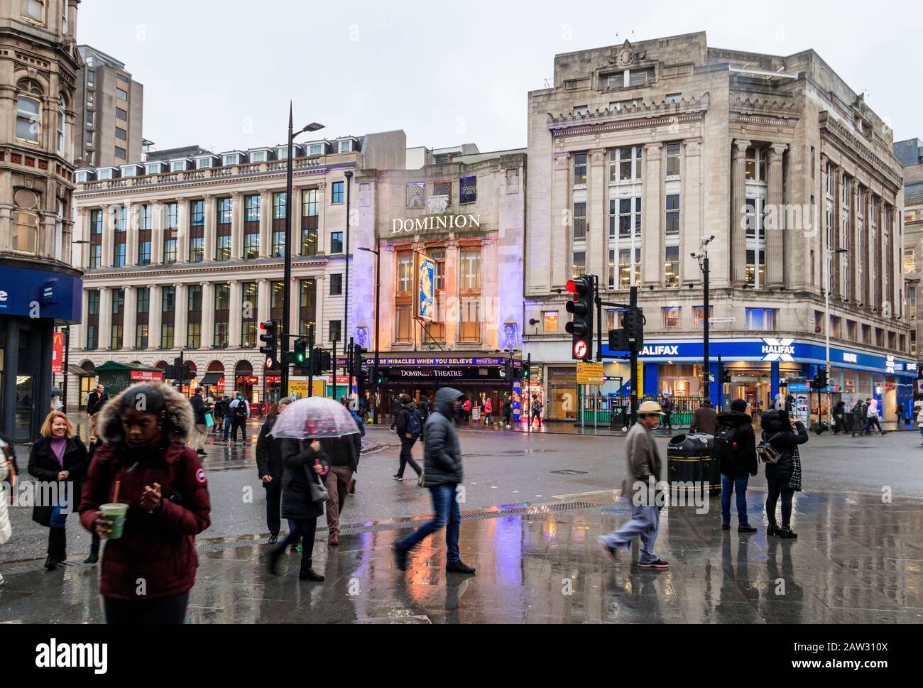 Commuters and tourists at the junction of Tottenham Court Road and Oxford Street on a rainy winter afternoon, London, UK Stock Photo