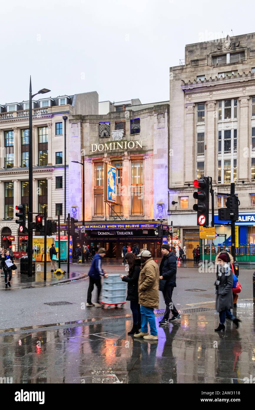 Commuters and tourists at the junction of Tottenham Court Road and Oxford Street on a rainy winter afternoon, London, UK Stock Photo