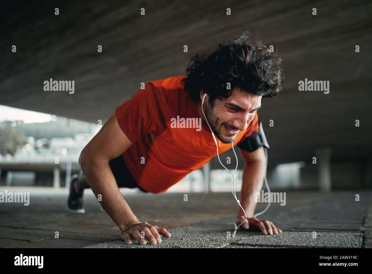Strong and highly motivated young sportsman doing push ups on pavement Stock Photo