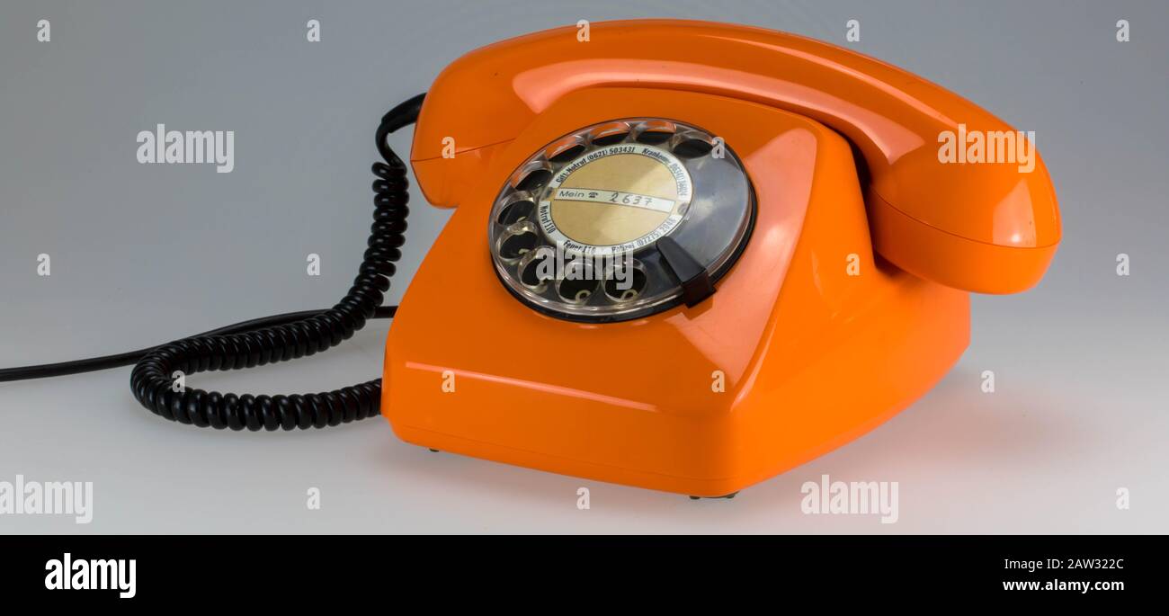 orange colored seventies retro telephone with dial Stock Photo