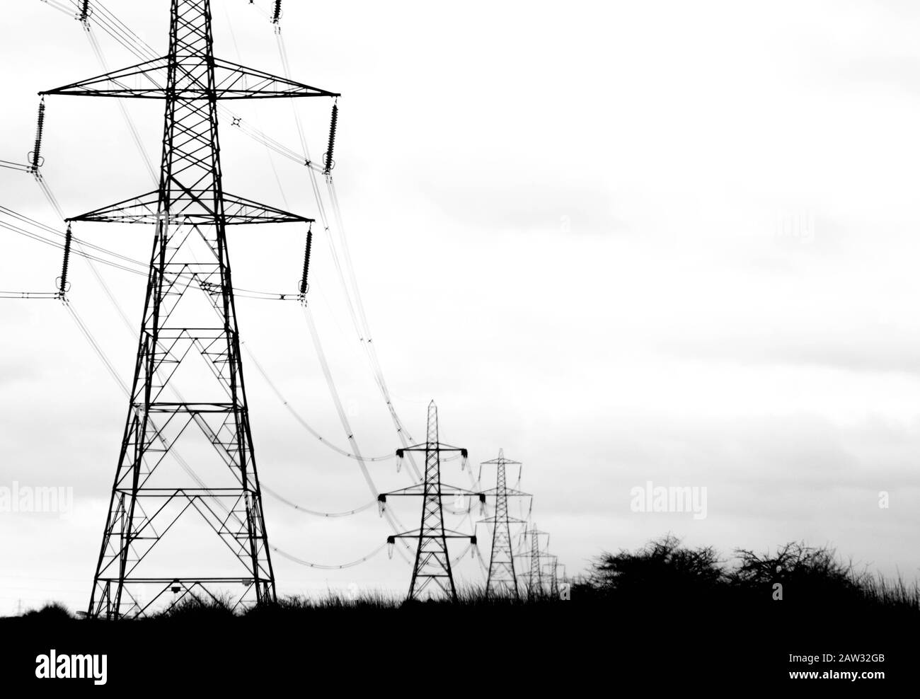 A row of electricity pylons stretch across the countryside, in the United Kingdom. Stock Photo