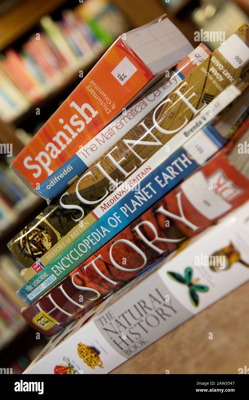 A pile of educational school books on a wooden table in a library Stock Photo