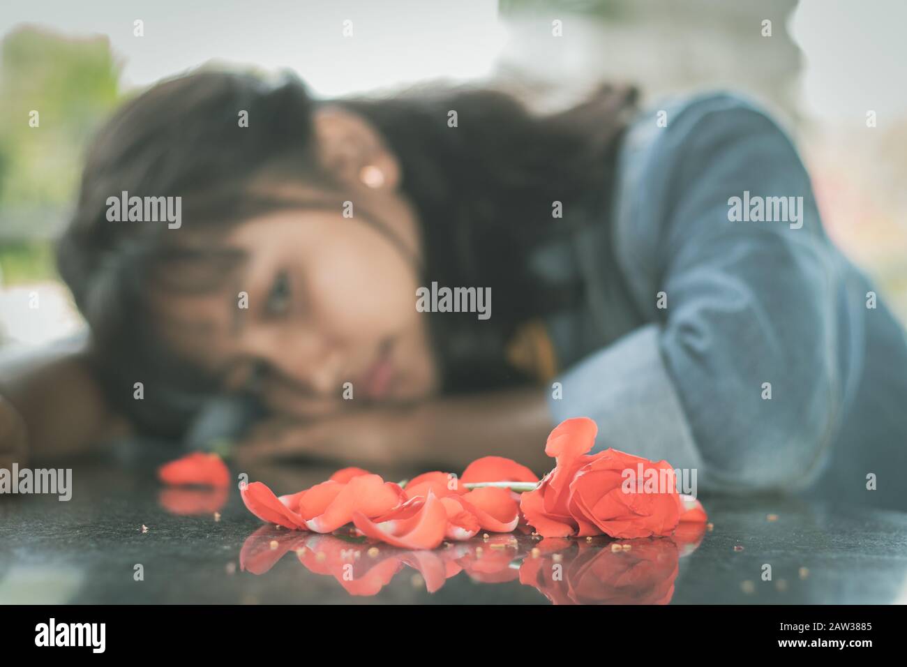 Selective focus on red rose lonely young teenager - concept of love breakup or broken heart. Stock Photo