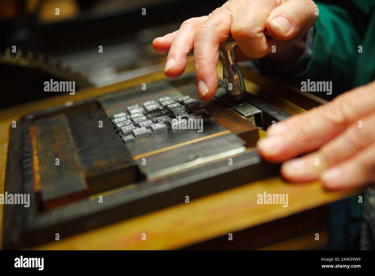 Printer secures a metal type block in a wood chase Stock Photo