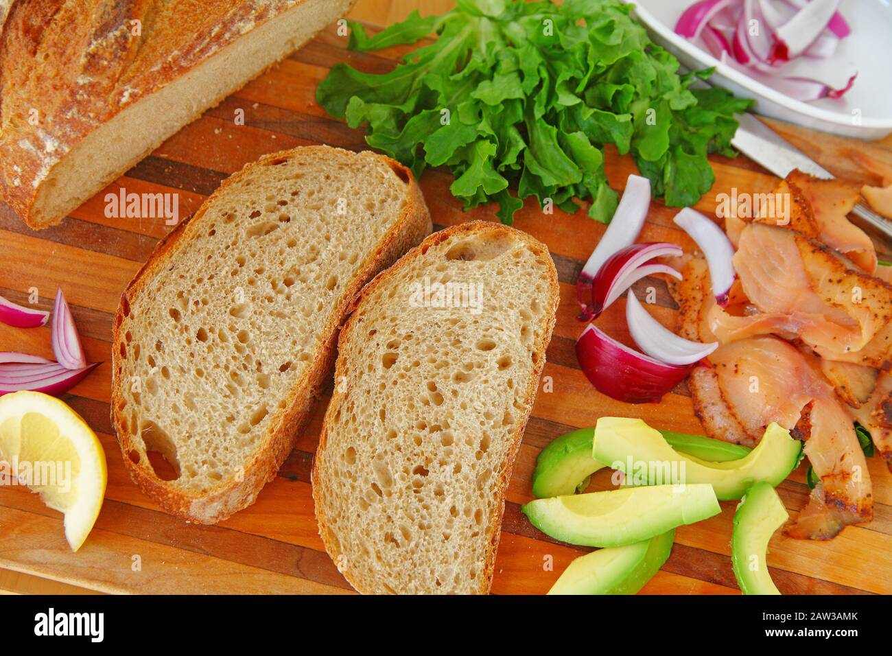 Making a smoked salmon sandwich with lettuce, onion and avocado on artisan bread Stock Photo