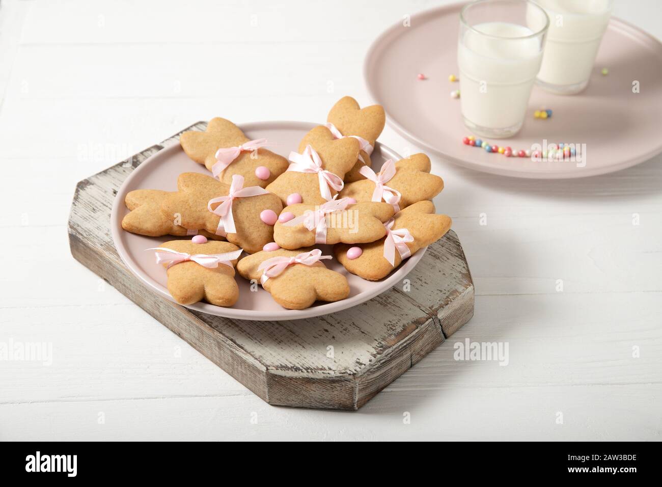 Easter cookies on a plate with a glass of milk on a wooden background. Easter bunnies. Stock Photo