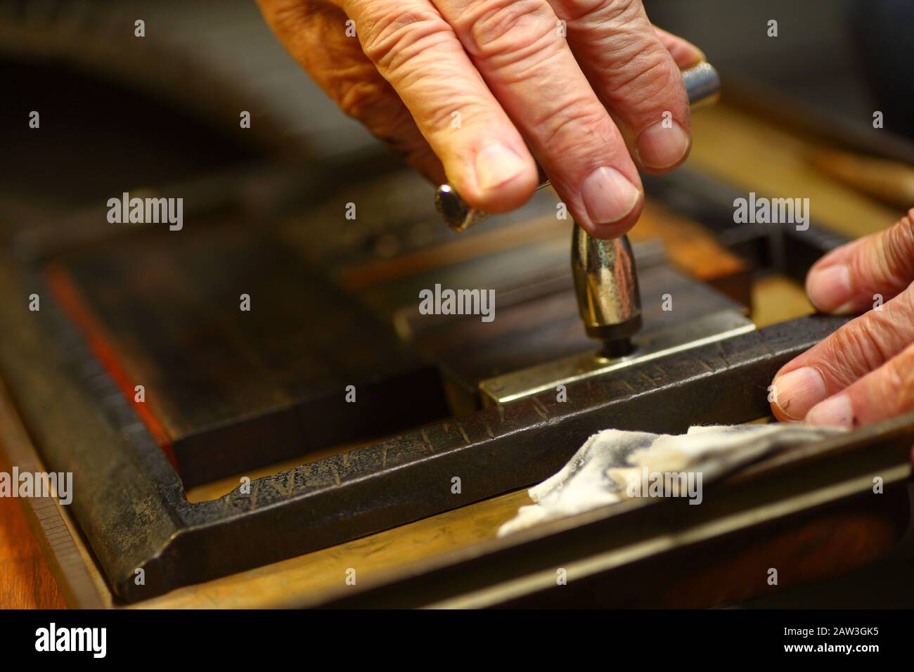 Closeup of ink-stained fingers of man using a quoin key to prepare type for letterpress printing Stock Photo