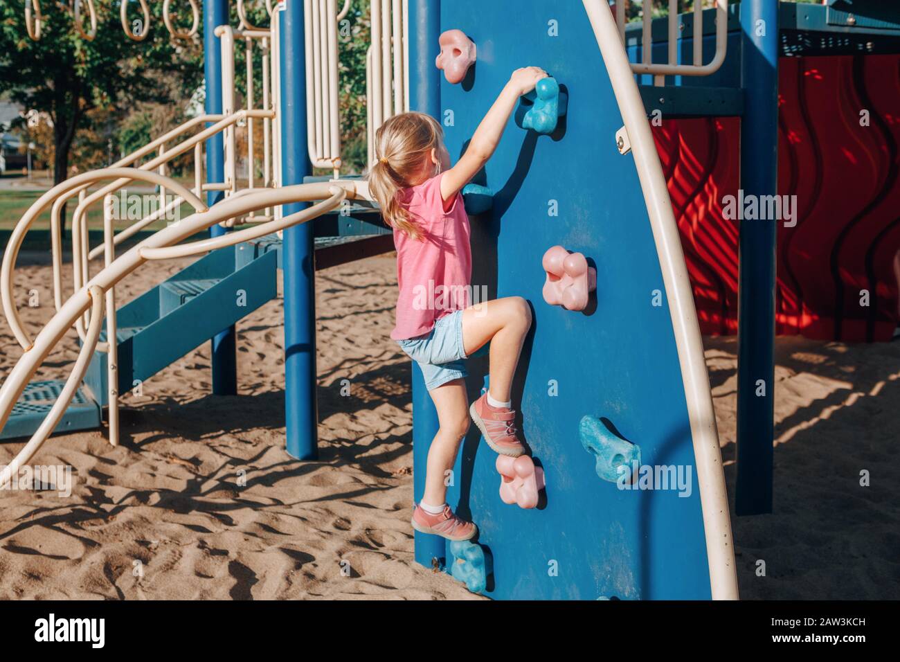 Little preschool girl climbing rock wall at playground outside on ...