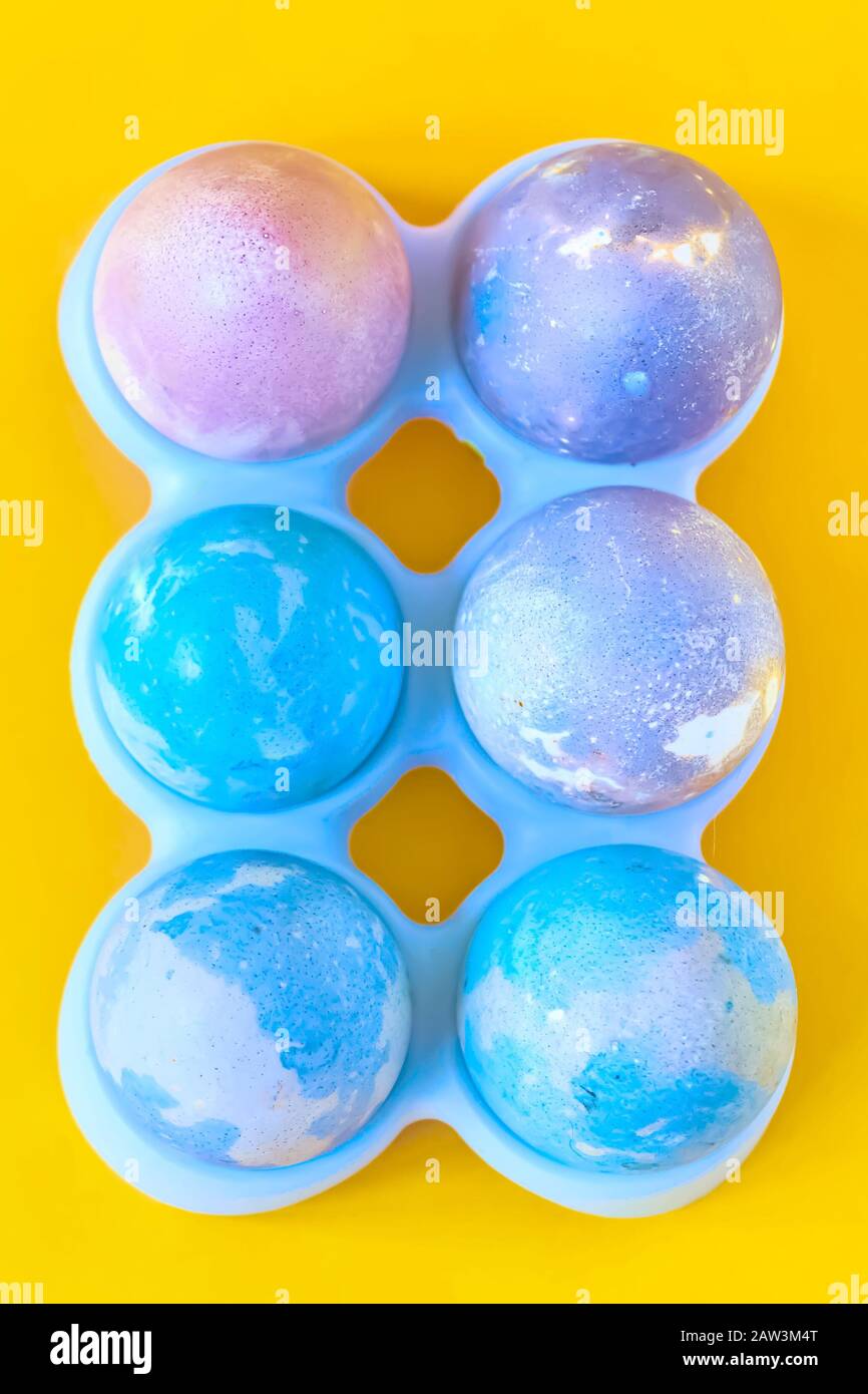 Painted Easter eggs with space intergalactic pattern in stand on yellow background Stock Photo