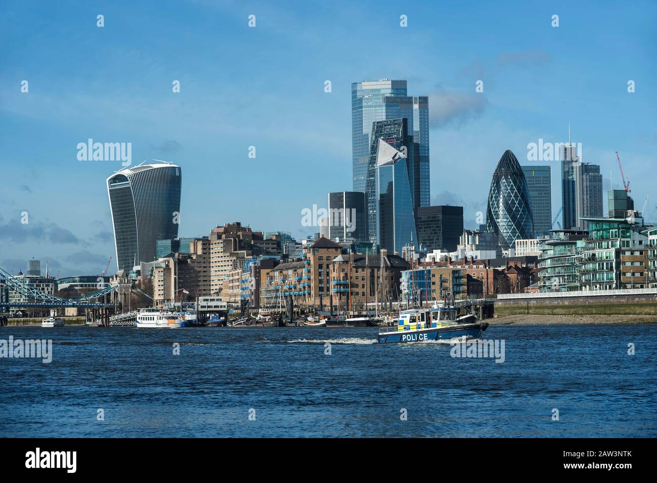 Cityscape of the the financial centre of The City of London from across The River Thames with a police launch heading downstream. Stock Photo