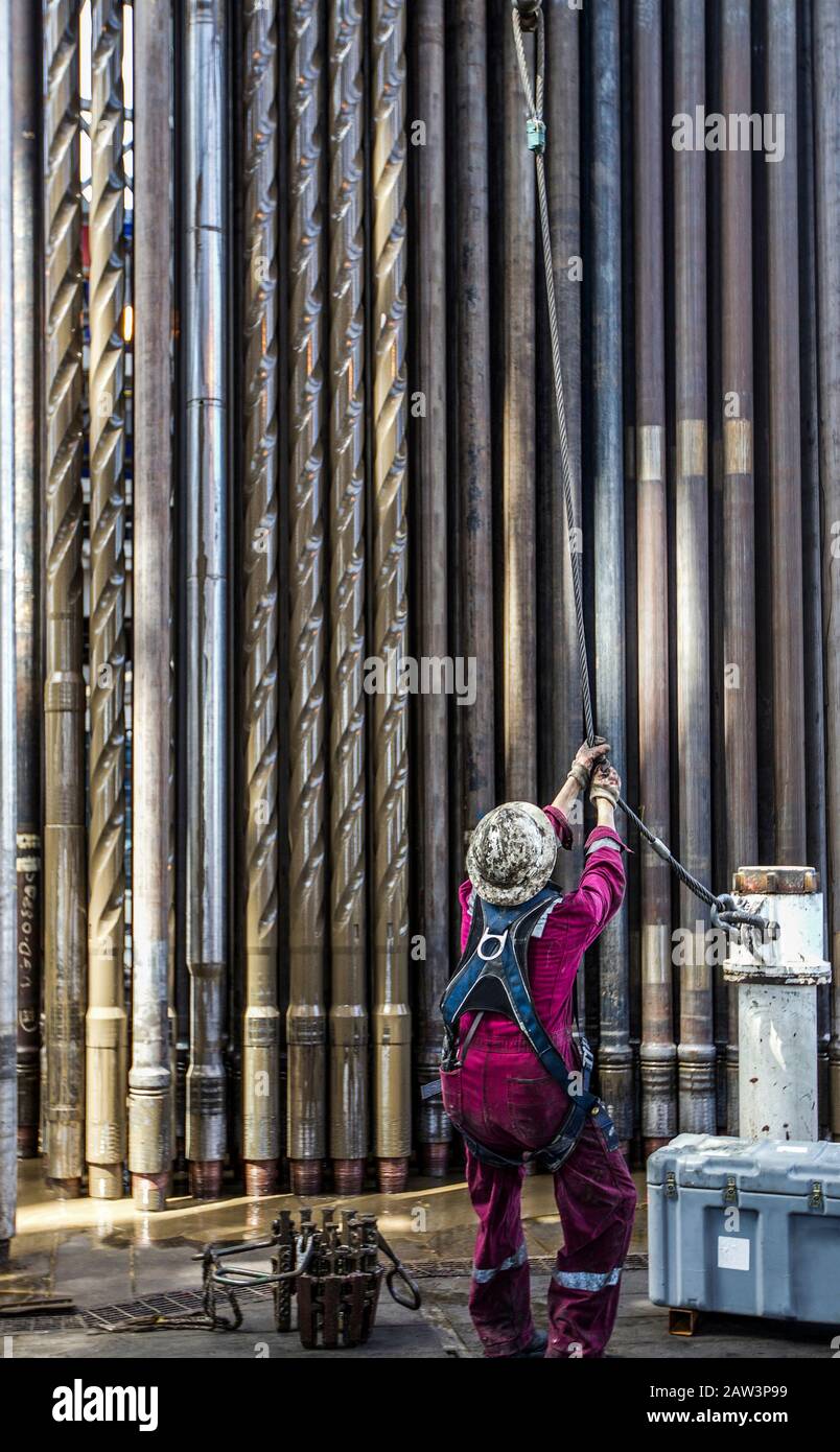 Worker prepping pipe for offshore drilling Stock Photo
