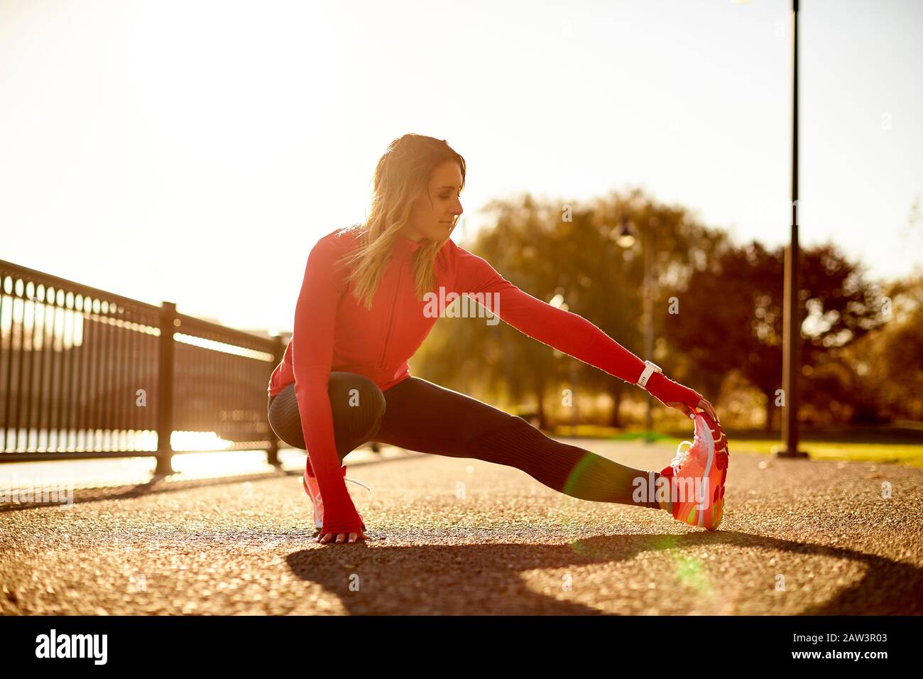 A female runner stretching in a city park Stock Photo - Alamy