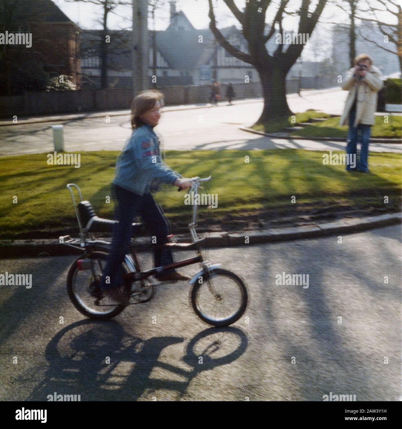 An 11 year old son being photographed by his dad riding his new American export Raleigh Chopper bike in 1973 in the suburbs of London UK. Stock Photo