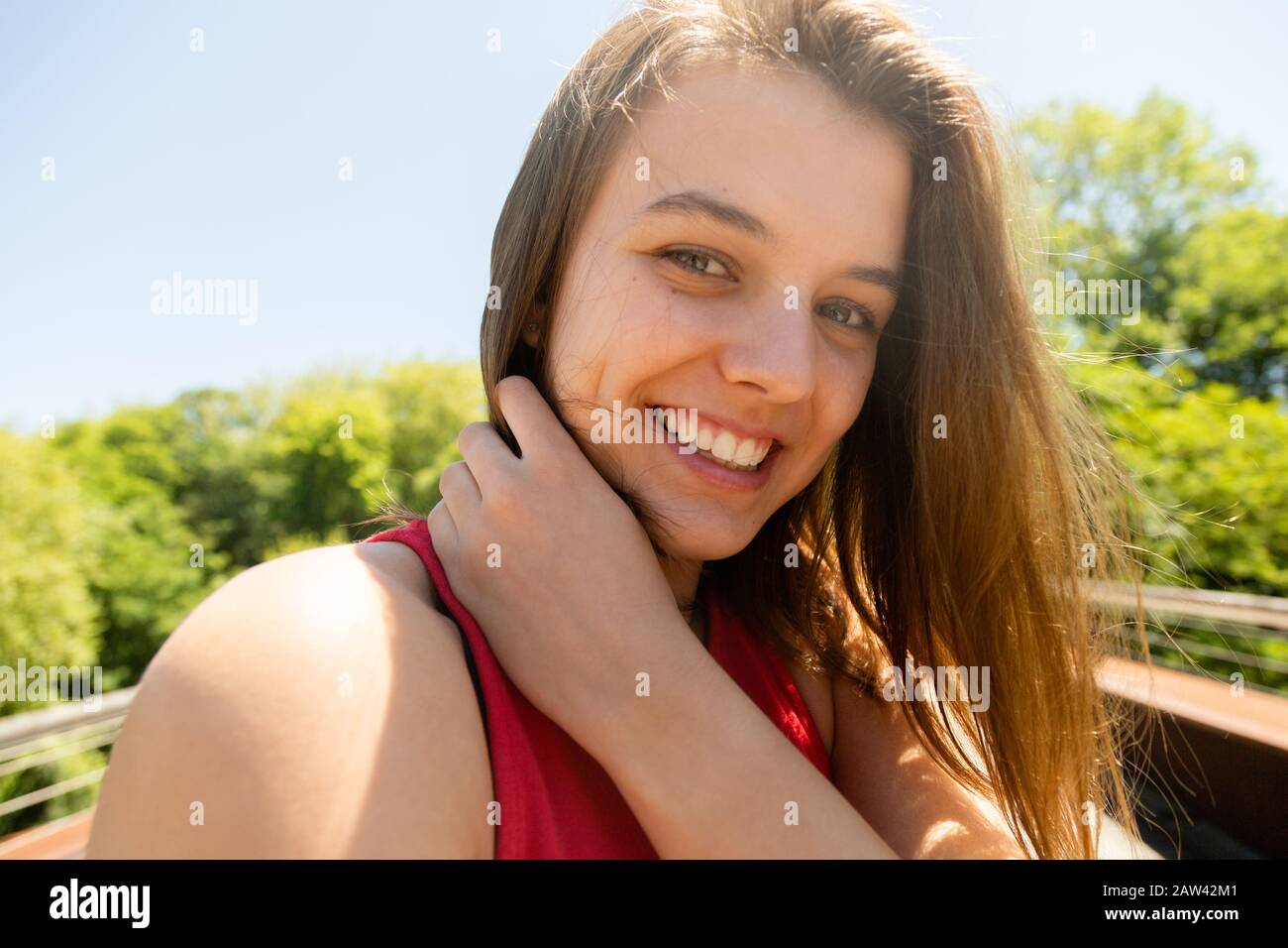 Portrait of a laughing young woman with messy hair because of the wind in a sunny day. Enjoyment in nature Stock Photo