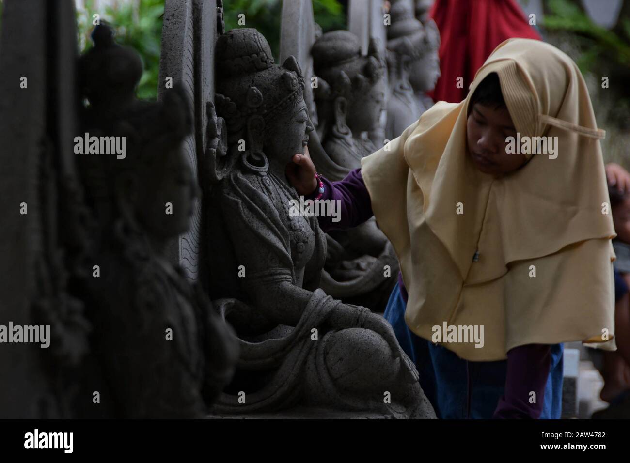 Local tourists visit the sleeping Buddha statue at Maha Vihara Mojopahit, Trowulan, Mojokerto, East Java, Indonesia. on March 7, 2019. The statue is 22 meters long, 6 meters wide and 4.5 meters high and is claimed to be the third largest Sleeping Buddha statue in Asia and is one of the tourist destinations. Stock Photo