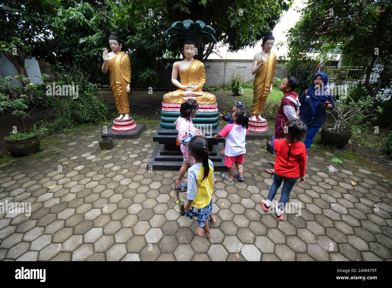 Local tourists visit the sleeping Buddha statue at Maha Vihara Mojopahit, Trowulan, Mojokerto, East Java, Indonesia. on March 7, 2019. The statue is 22 meters long, 6 meters wide and 4.5 meters high and is claimed to be the third largest Sleeping Buddha statue in Asia and is one of the tourist destinations. Stock Photo