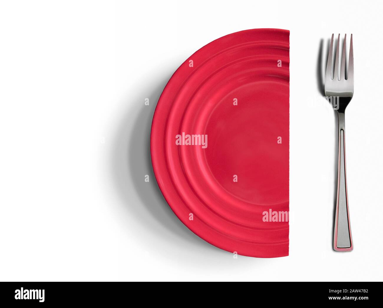 Halved red dish next to a fork on white surface. Copy-space. Stock Photo